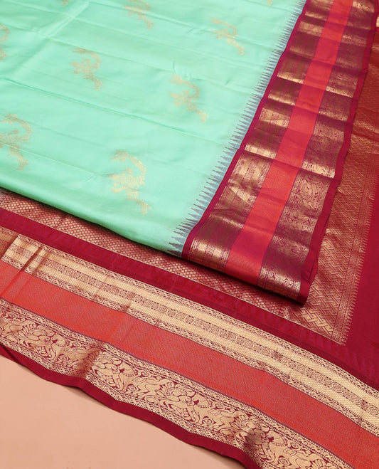 Turquoise Vasundhara Silk Saree, Meticulously Crafted with Zari Buttas on Its Body, Complemented by Contrast Border of Muthu, Mayil Kann, Chakram, Mayil, and Kuthirai Designs, an Intricately Designed Pallu, and Paired with a Contrast Blouse