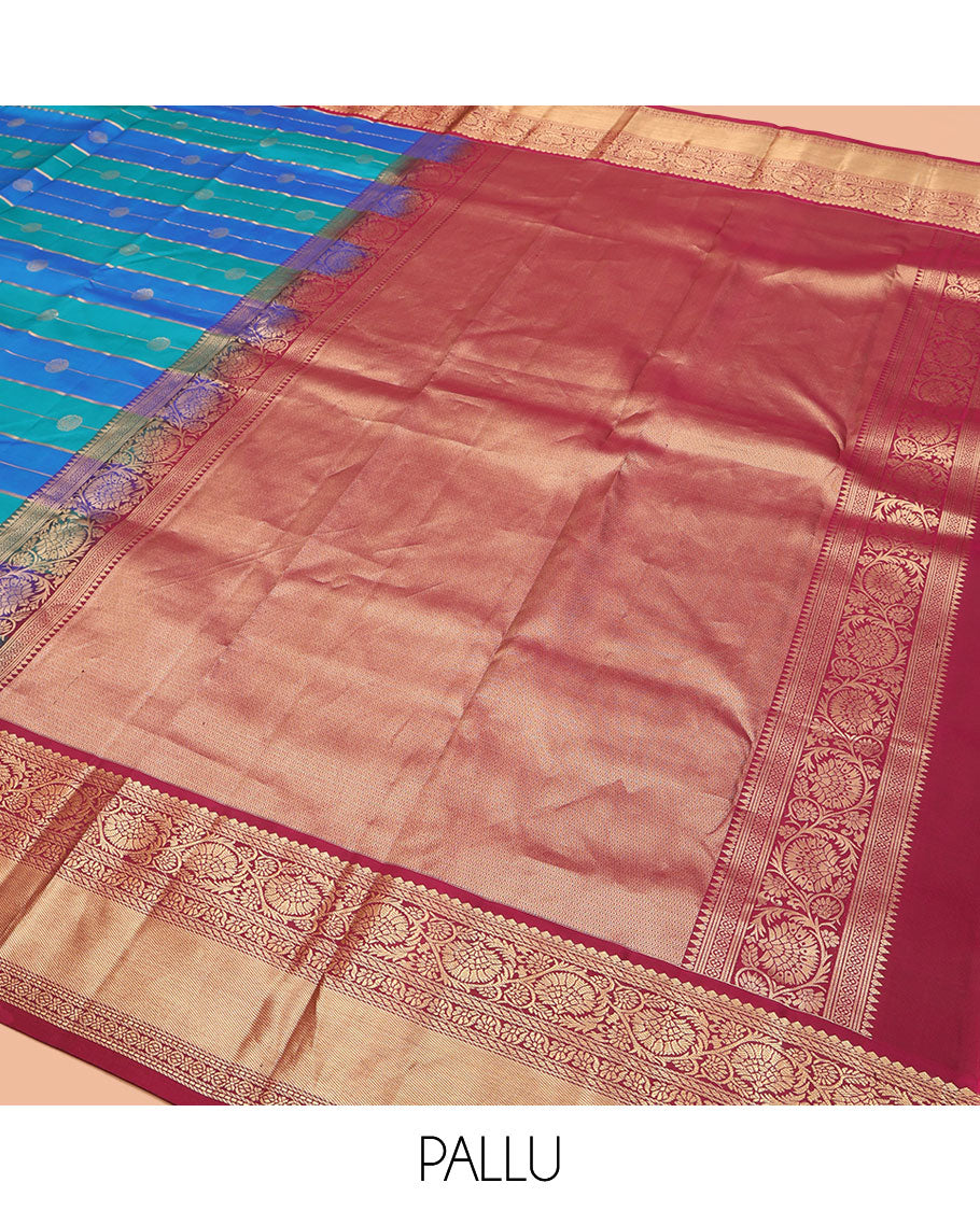 Blue Vasundhara Silk Saree, Impeccably Styled with Zari Buttas and Zari Stripes All Over Its Body, Complemented by a Contrast Border of Salngai, Puli Nagam, and Kodi Visiry Designs, Grand Gleaming Zari Woven Pallu, and Paired with a Contrast Blouse