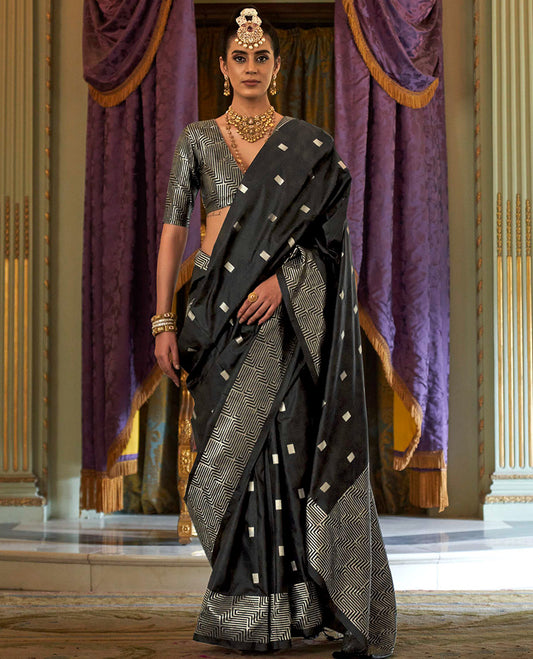 Black Designer Catalog Saree Gleamed up with Square Buttas All Over Its Body, Highlighted with a Zari Border of Maze-Like Geometric Patterns, Pallu Mirrors Intricate Maze patterns in Zari, and Paired with a Matching Blouse