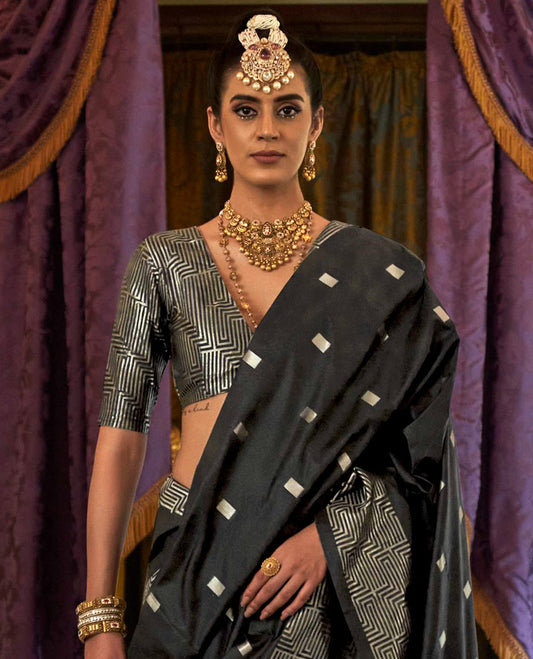 Black Designer Catalog Saree Gleamed up with Square Buttas All Over Its Body, Highlighted with a Zari Border of Maze-Like Geometric Patterns, Pallu Mirrors Intricate Maze patterns in Zari, and Paired with a Matching Blouse