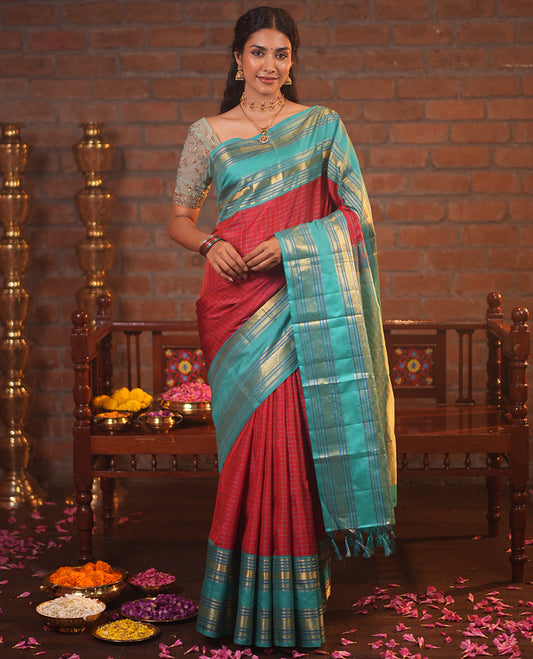 Tomato Red and Blue Vasundhara Silk Saree, Subtly Sparkled With Pattu Nool Kattam On Its Body, Complemented by Contrast Rettai Pettu Border of Salngai, Muthu, Neli, Rudraksham, and Dhavana Kodi Designs, Grand Pallu and Paired with a Contrast Blouse