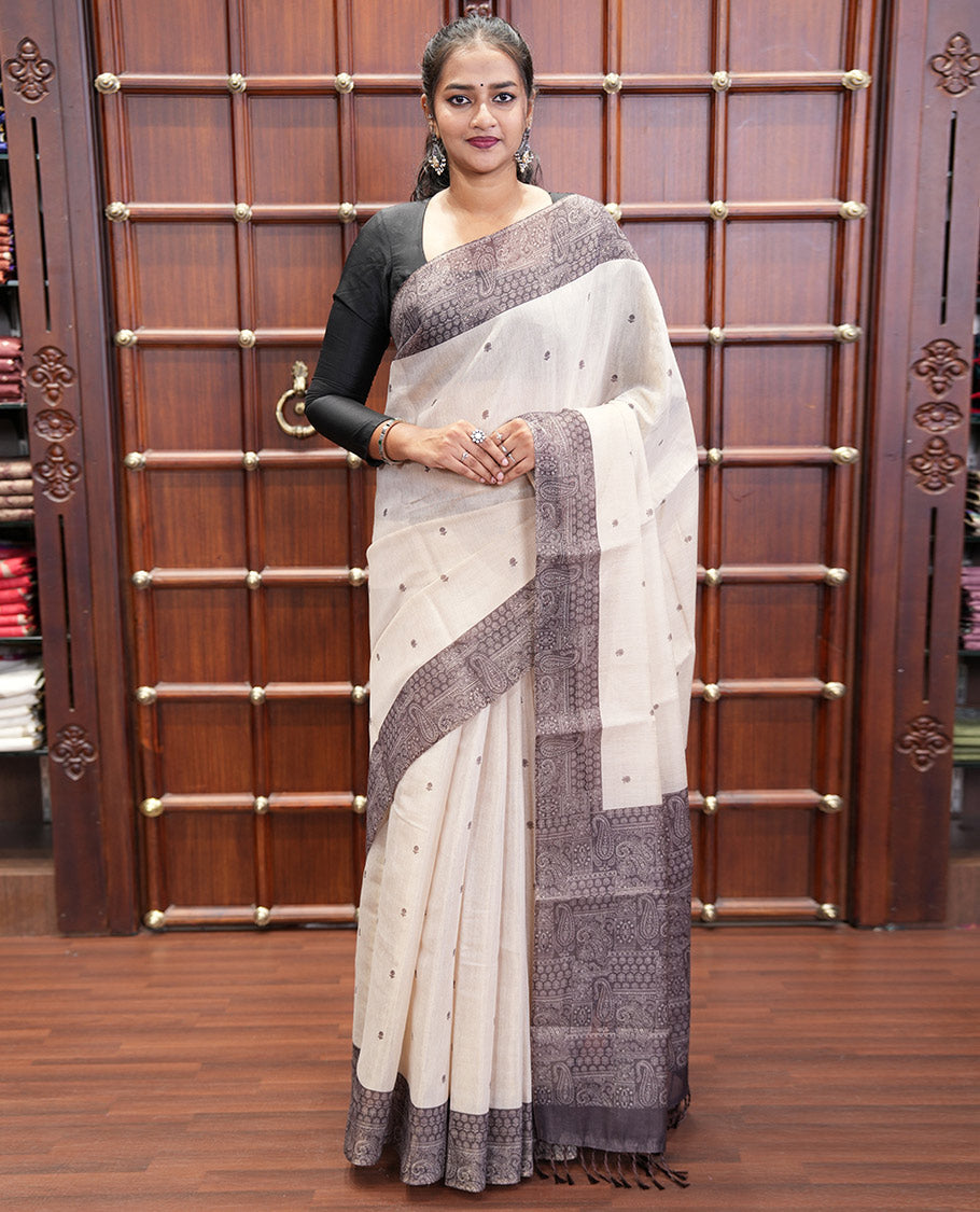 Chikku and Black Tissue Linen Saree, Delicately Printed with Floral Motifs on Its Body, Complemented by a Contrast Border of Paisley Designs, Pallu Steeped with Paisley Designs, and Paired with a Contrast Blouse