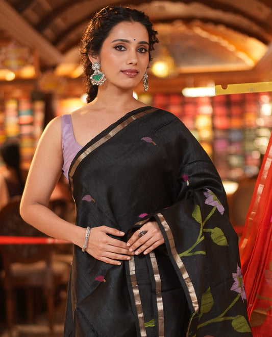 Black Matka Silk Saree, Artfully Woven With Jamdani-Style Leaf Motifs and Floral Design On Its Body, Subtle Piping Border, Tissue Pallu of Jamdani Floral Weave, and Paired with a Contrast Blouse