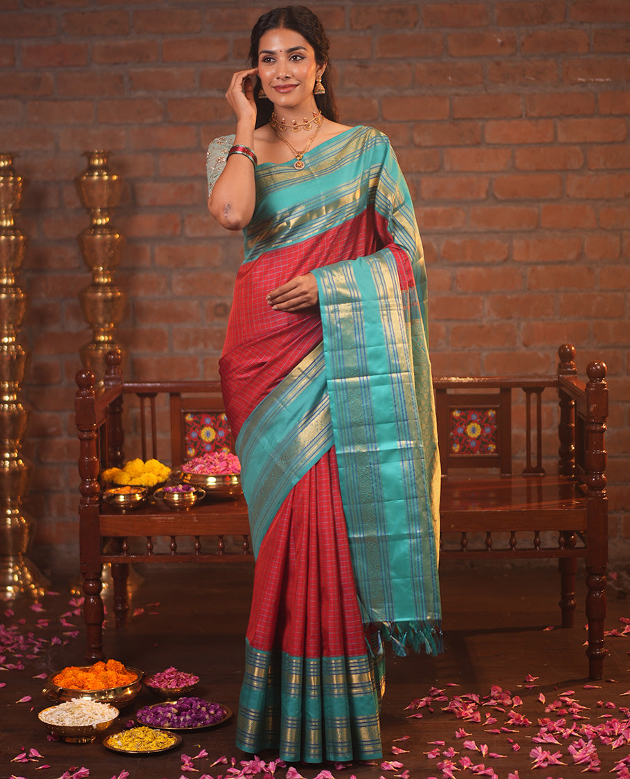 Tomato Red and Blue Vasundhara Silk Saree, Subtly Sparkled With Pattu Nool Kattam On Its Body, Complemented by Contrast Rettai Pettu Border of Salngai, Muthu, Neli, Rudraksham, and Dhavana Kodi Designs, Grand Pallu and Paired with a Contrast Blouse