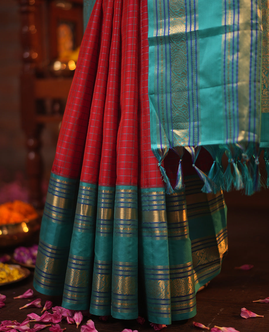 Tomato Red and Blue Vasundhara Silk Saree, Subtly Sparkled With Pattu Nool Kattam On Its Body, Complemented by Contrast Rettai Pettu Border of Salngai, Muthu, Neli, Rudraksham, and Dhavana Kodi Designs, Grand Pallu and Paired with a Contrast Blouse