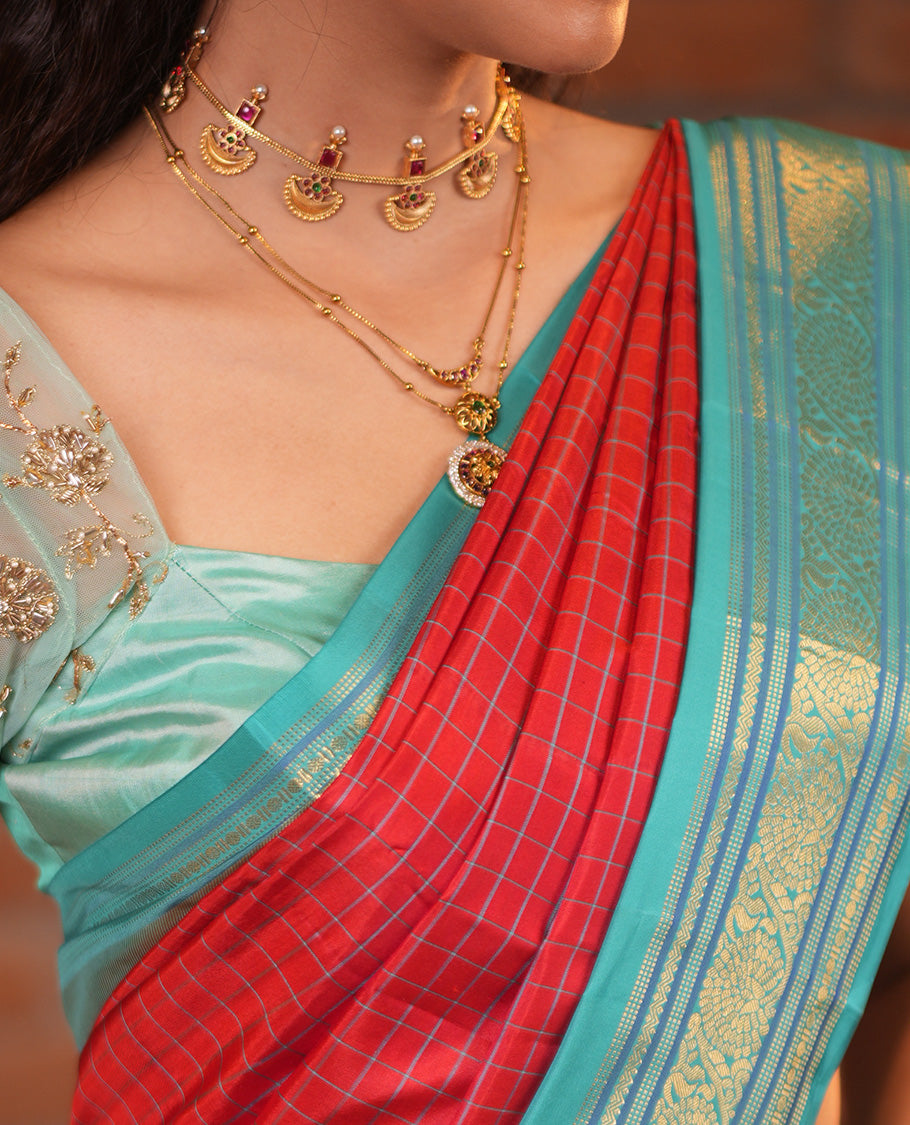 Tomato Red and Blue Vasundhara Silk Saree, Subtly Sparkled With Pattu Nool Kattam On Its Body, Complemented by Contrast Rettai Pettu Border of Salngai, Muthu, Neli, Rudraksham, and Dhavana Kodi Designs, Grand Pallu and Paired with a Contrast Blouse