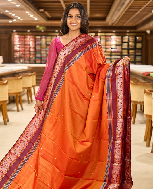 Orange thread buttas Kanchipuram silk saree, contrast rettai pettu border of rekku, rudraksham, yaanai, and Pichwai cow designs, and pallu features Vrishabha Kunjara design