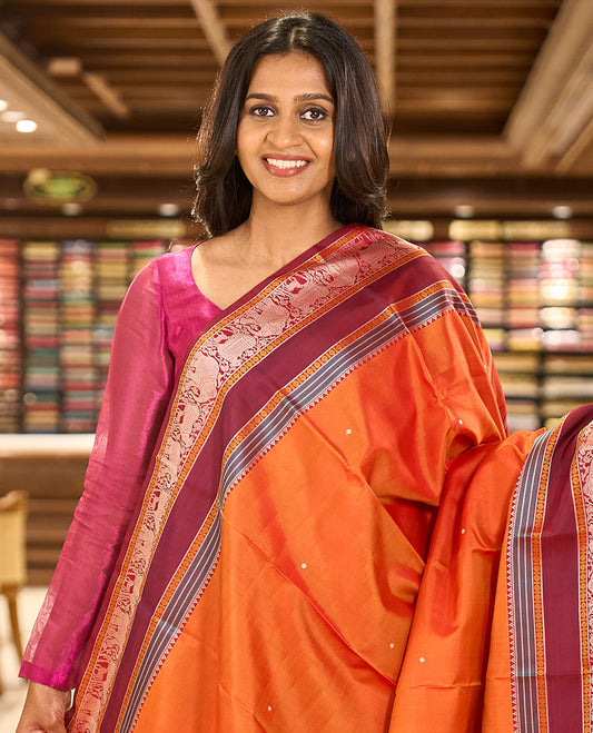 Orange thread buttas Kanchipuram silk saree, contrast rettai pettu border of rekku, rudraksham, yaanai, and Pichwai cow designs, and pallu features Vrishabha Kunjara design