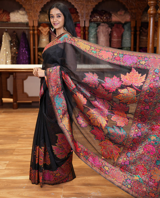 Black kaleidoscopic floral motifs woven pashmina saree, kaleidoscopic floral border, Mughal style patterned pallu, and a colorful leaf jaal blouse