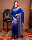 Blue Vasundhara Silk Saree Gleamed with Zari Buttas All Over Its Body, Highlighted with a Zari Border of Thilakam Mokku, Muthu, Cross Kamalam, and Mayil Kann Designs, Grand Pallu of Jaal Design, and Paired with a Matching Blouse