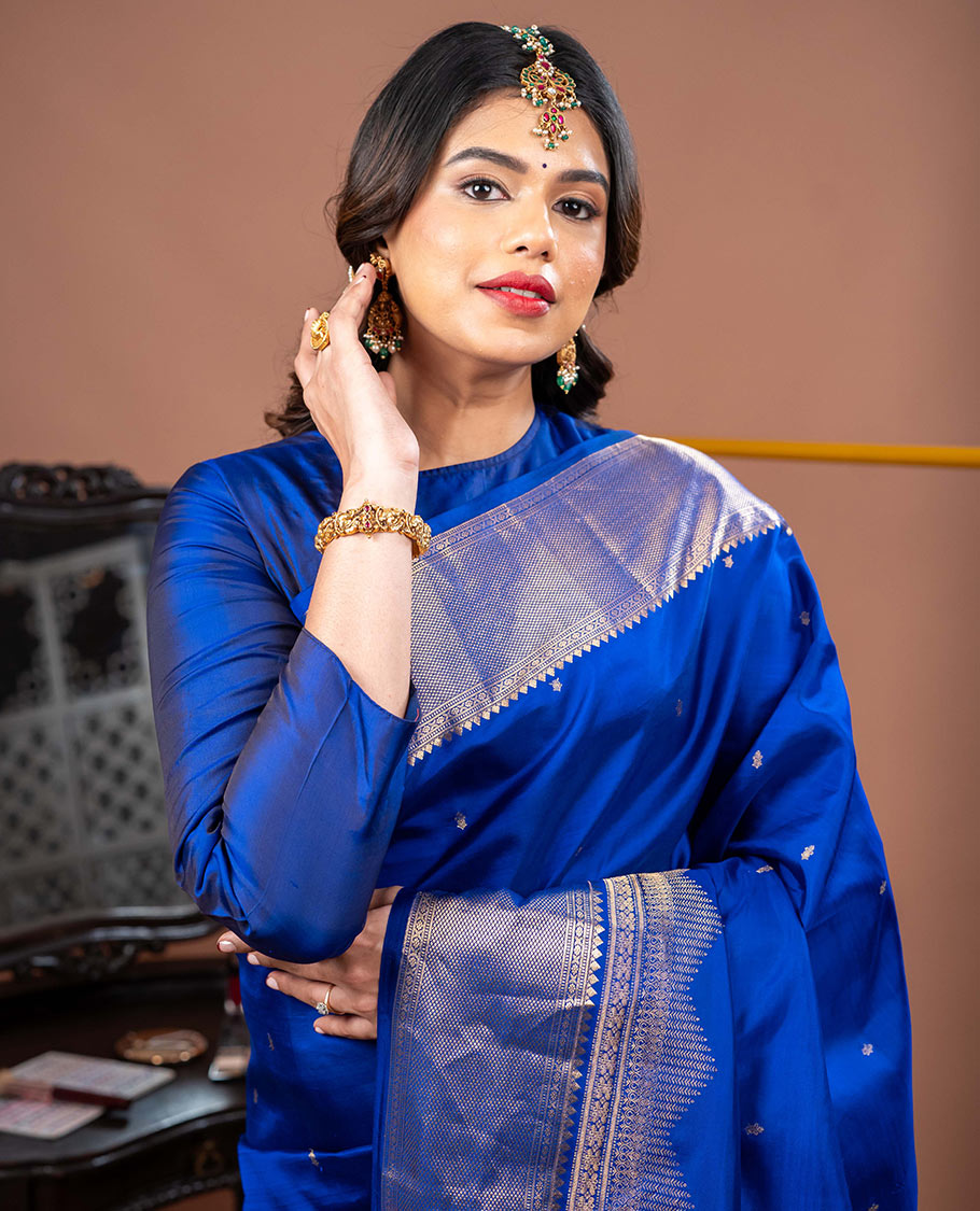 Blue Vasundhara Silk Saree Gleamed with Zari Buttas All Over Its Body, Highlighted with a Zari Border of Thilakam Mokku, Muthu, Cross Kamalam, and Mayil Kann Designs, Grand Pallu of Jaal Design, and Paired with a Matching Blouse