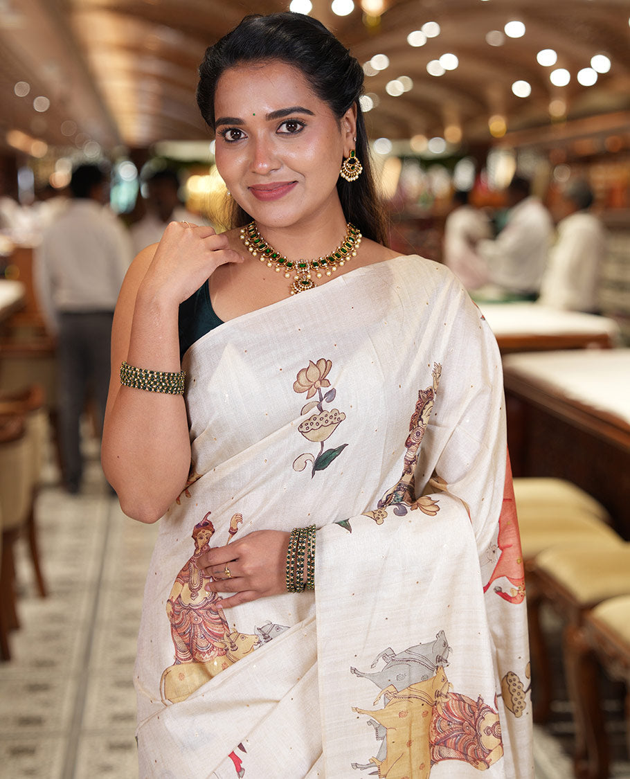 Borderless Cream Semi-Tussar Saree, Artfully Printed with Ancient Human Figurines, Floral, and Pichwai Cow on Its Body, Highlighted by Kalamkari-Style Human Motifs Printed Pallu, and Paired with a Matching Pichwai Cow Printed Blouse
