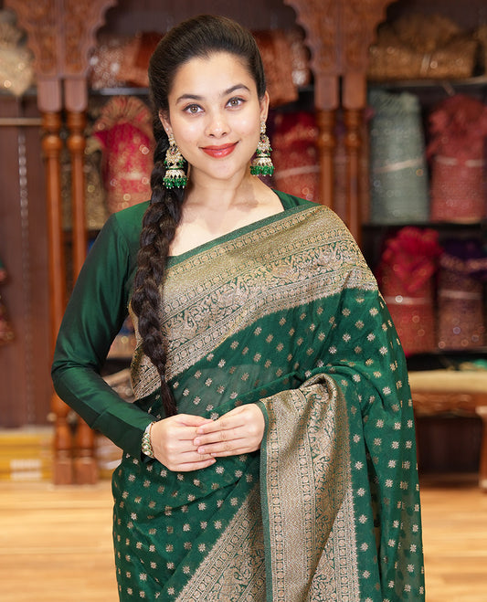 Green Semi-Banaras Khaddi Georgette, Finely Detailed with Zari Buttas All Over Its Body,  Subtly Sparkled Traditional Border of Rudraksham, Elephant, and Floral Vine Designs, Pallu of a Herd of Elephants, and Paired with a Matching Blouse