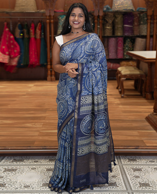 Indigo Blue Muslin Cotton Saree, Beautified with Round Peacock Motifs and Floral Print on Its Body, a Subtle Zari Border, Striped Pallu, and Matching Blouse