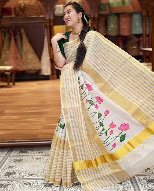 Cream Kerala Cotton Saree, Gleamed Up with Horizontal Zari Stripes and Pichwai Lotus Print All Over Its Body, Subtle Zari Border, Pallu Mirrors Pichwai Lotus Print, and Paired with a Matching Blouse