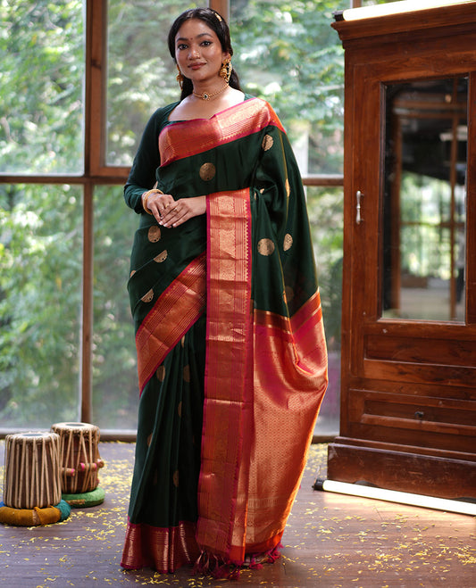 Green Vasundhara Silk Saree, Elevated with Mayil Zari Buttas All Over Its Body, Complemented by a Contrast  Border of Thilakam Mokku, Kathir, and Round Mayil Designs, Grand Jaal Pallu, and Paired with a Contrast Blouse