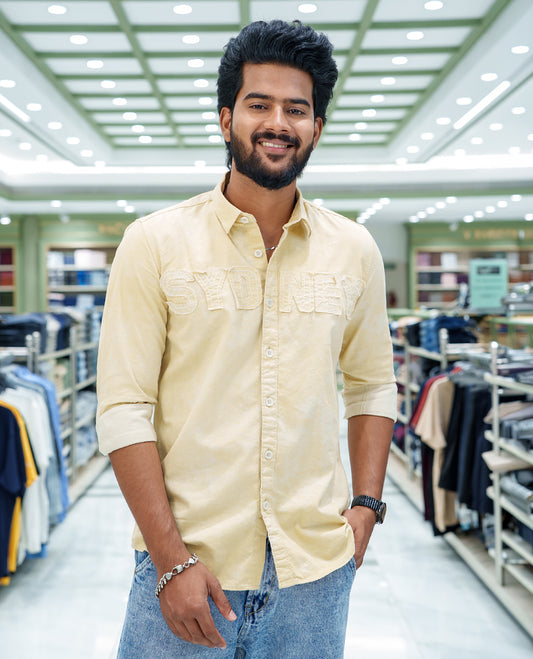 Cream Cotton Blended Casual Shirt, Bedecked with Acid-Washed and Typography Patch Embroidery on the Chest, Featuring a Spread Collar, Full Sleeves, Slim Fit, and Regular Length
