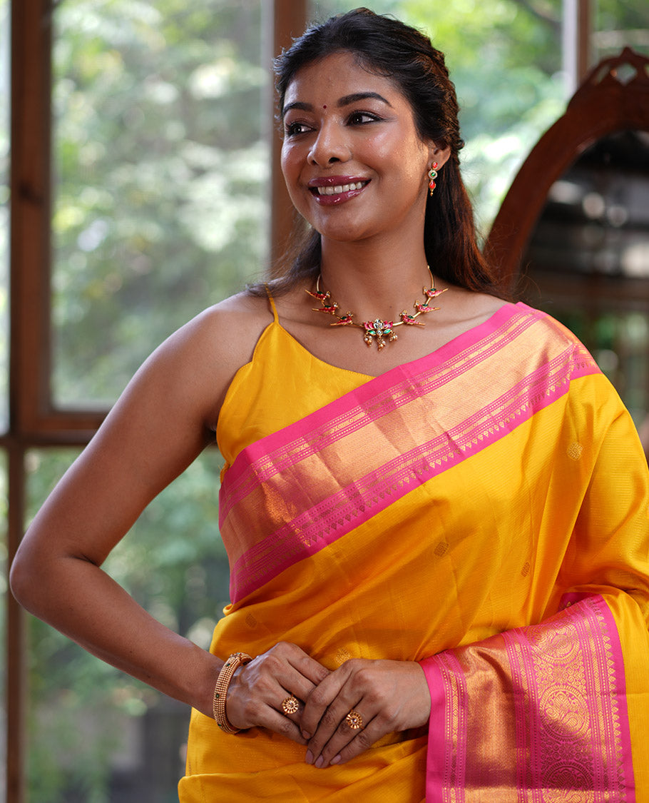 Mango Yellow Vasundhara Silk Saree, Subtly Sparkled with Sparse Stripes and Zari Buttas, Complemented by a Contrast Border of Thilakam, Banaras, Muthu, and Round Mayil Designs, Pallu Steeped with Traditional Designs, and Paired with a Contrast Blouse
