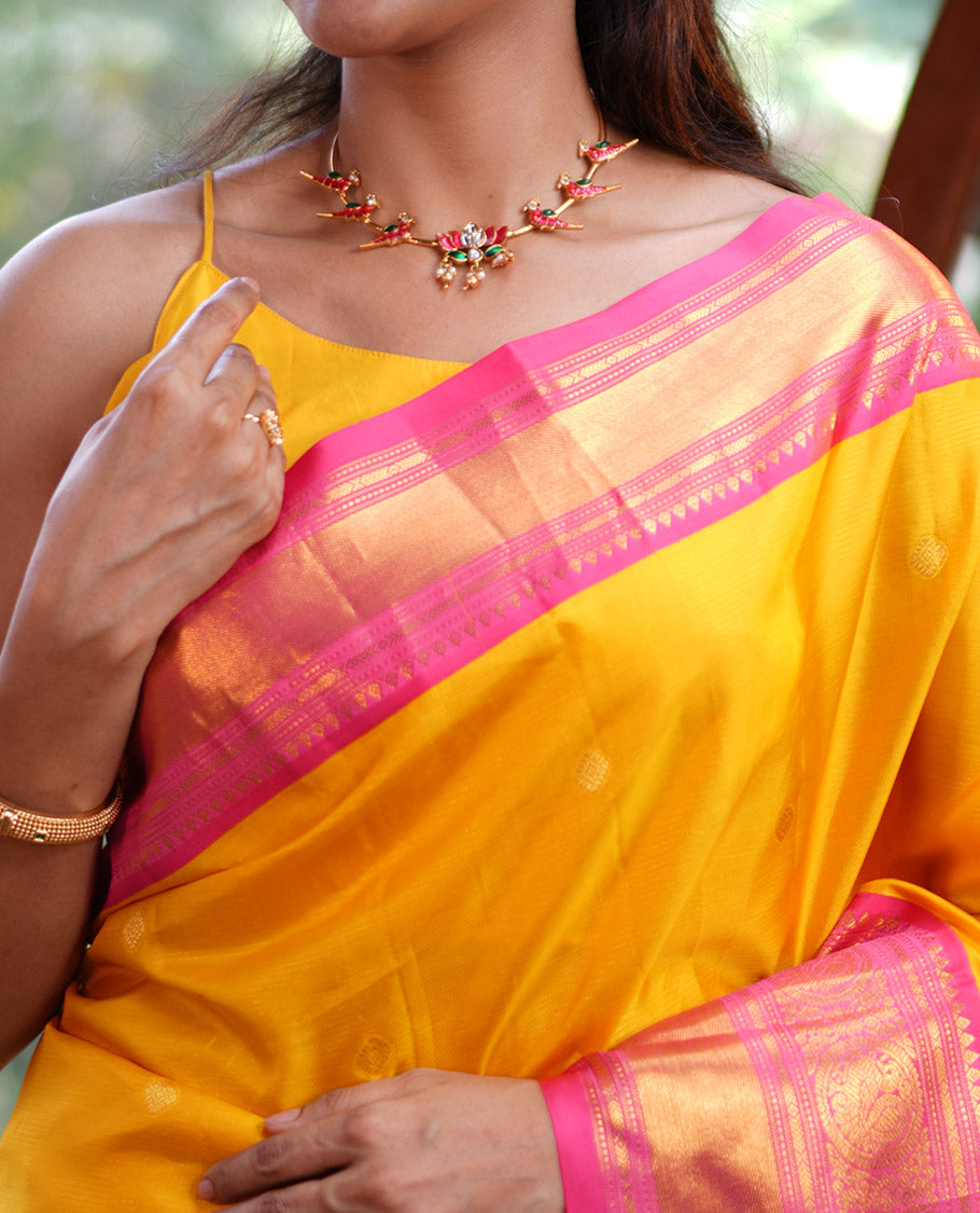 Mango Yellow Vasundhara Silk Saree, Subtly Sparkled with Sparse Stripes and Zari Buttas, Complemented by a Contrast Border of Thilakam, Banaras, Muthu, and Round Mayil Designs, Pallu Steeped with Traditional Designs, and Paired with a Contrast Blouse