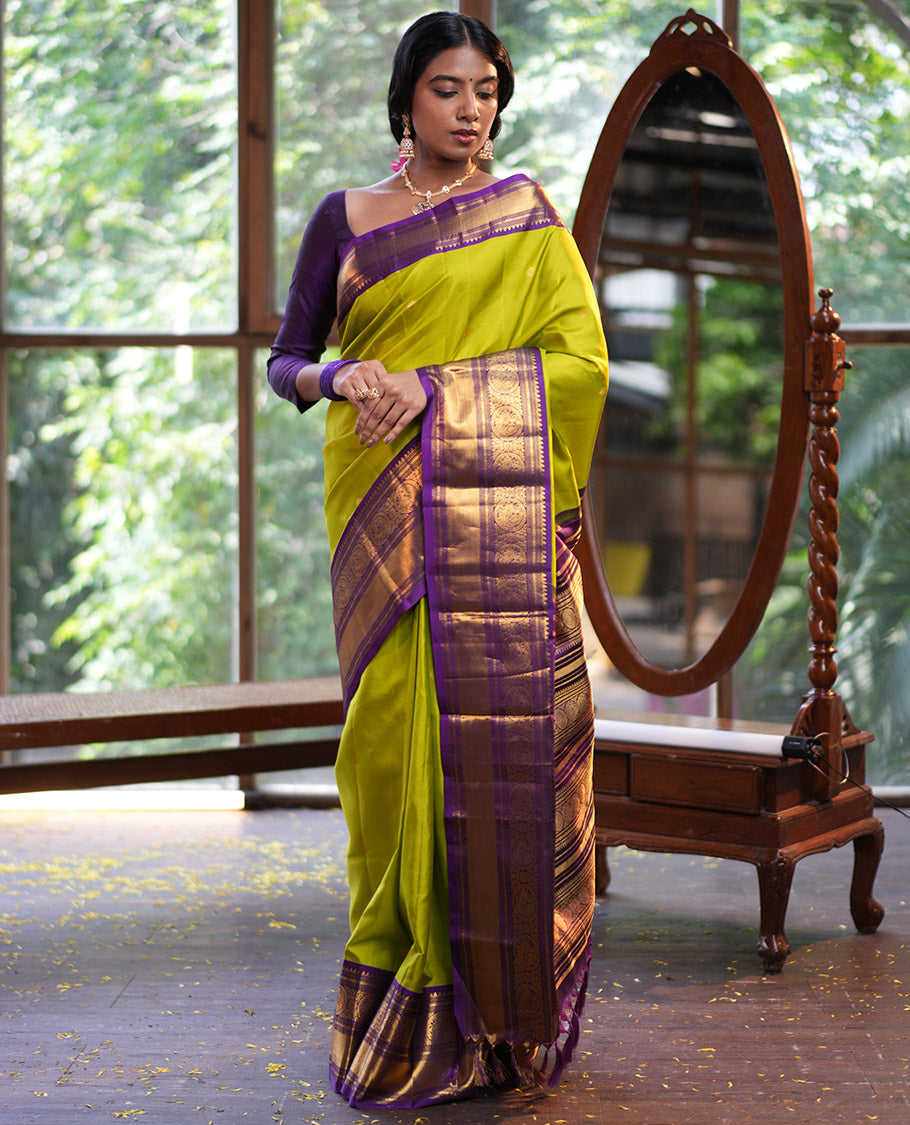 Parrot Green Vasundhara Silk Saree, Enriched with Sparse Stripes and Zari Buttas, Complemented by a Contrast Border of Thilakam, Banaras, Muthu, and Round Mayil Designs, Pallu Steeped with Traditional Designs, and Paired with a Contrast Blouse