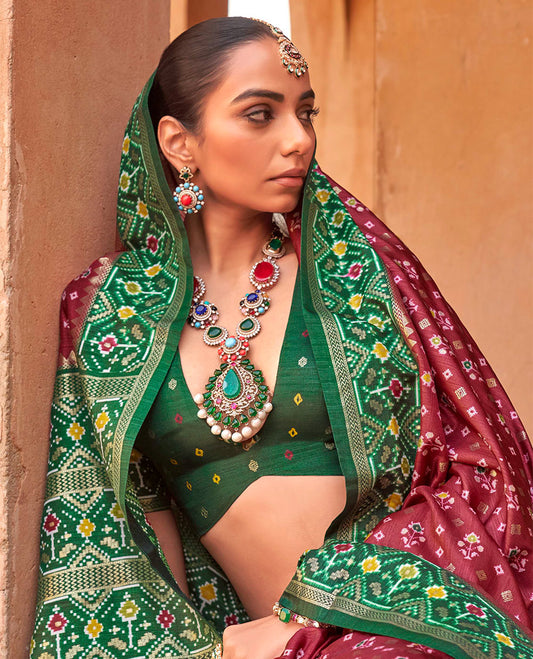 Maroon Ikat Patola Designer Saree, Ornamented with Floral Ikat Buttas, Complemented by a Contrast Ikat Border, Intricate Pallu, and a Contrast Blouse