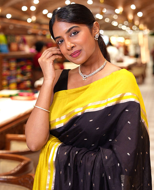 Black Assam Silk Saree, Ornamented with Zari Buttas on Its Body, Complemented by Contrast Zari Striped Border, Pallu Steeped with Gleaming Zari Stripes and Buttas, and Paired with a Contrast Blouse