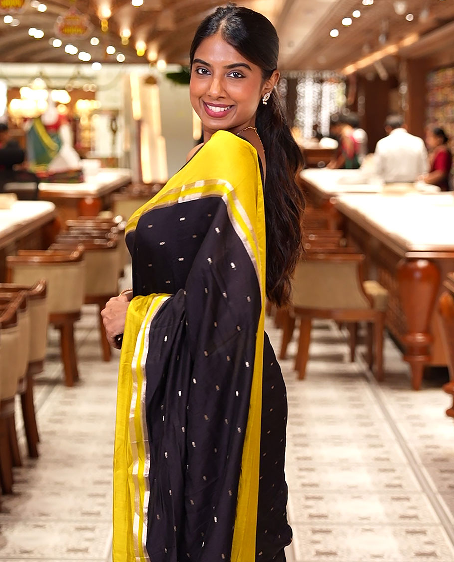 Black Assam Silk Saree, Ornamented with Zari Buttas on Its Body, Complemented by Contrast Zari Striped Border, Pallu Steeped with Gleaming Zari Stripes and Buttas, and Paired with a Contrast Blouse