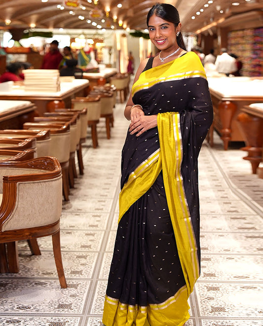 Black Assam Silk Saree, Ornamented with Zari Buttas on Its Body, Complemented by Contrast Zari Striped Border, Pallu Steeped with Gleaming Zari Stripes and Buttas, and Paired with a Contrast Blouse