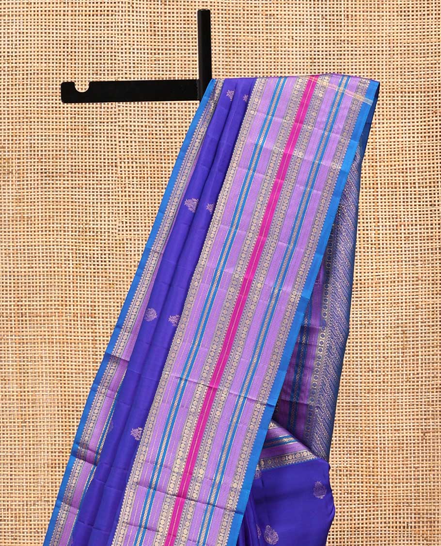 Violet and Mayil Blue Vasundhara Silk Saree, Subtly Sparkled with Zari Buttas All Over Its Body, Highlighted by Self-Border of Thilakam Mokku, Rudraksham, Muthu, and Mayil Kann Designs, Diagonally Striped Pallu, and Paired with a Matching Blouse