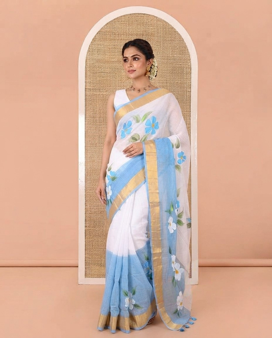 White and Blue Khadi Mul Cotton Saree, Adorned with Hand-Brush Painting-Style Floral Block Printed Body, a Subtle Gold Zari Border, a Self-Pallu, and Paired with a Matching Blouse