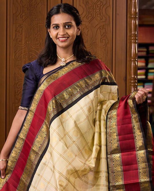 Cream iruthalai pakshi, and chakram buttas enclosed zari checked Kanchipuram silk saree, contrast rettai pettu border of salngai, muthu, and jadai nagam designs