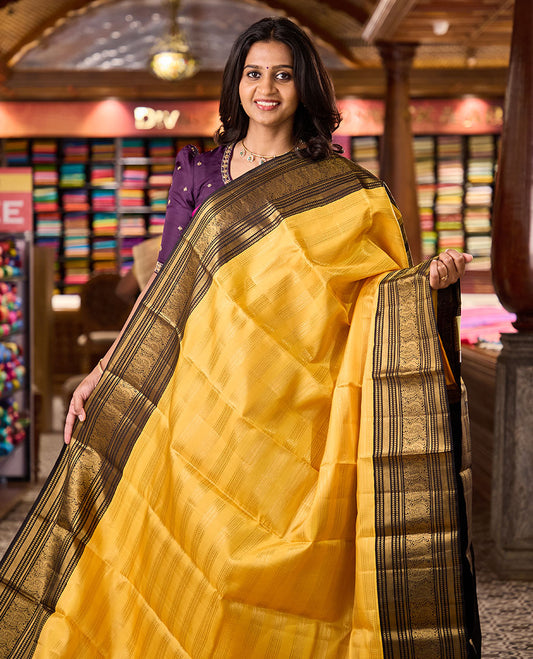 Yellow zari striped Kanchipuram silksaree, contrast border of kathir, and mayil designs, and pallu of mayil kann designs
