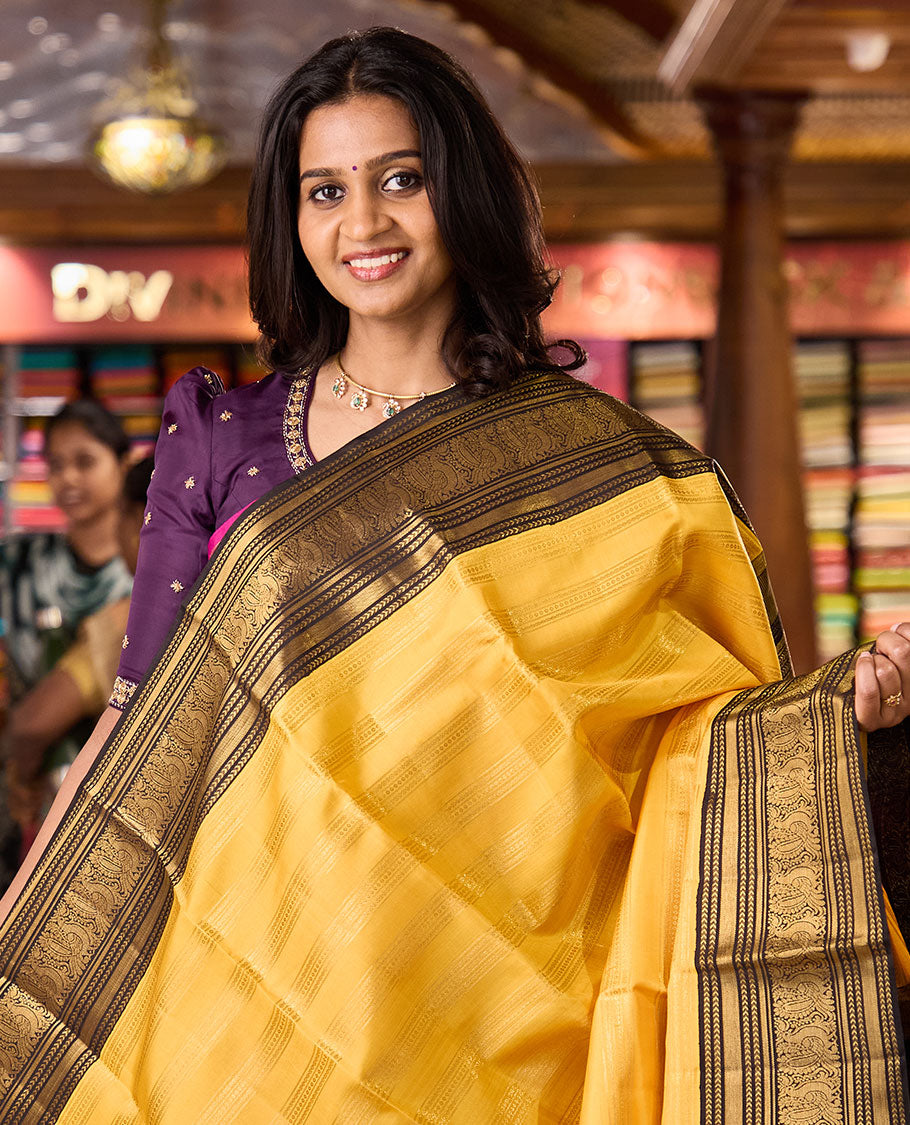 Yellow zari striped Kanchipuram silksaree, contrast border of kathir, and mayil designs, and pallu of mayil kann designs