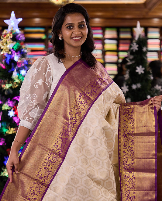 Cream jacquard silk saree, contrast vanasingaram style border of thilakam mokku, kodi visiry, mayil, maan, and yaanai designs, and intricate pallu