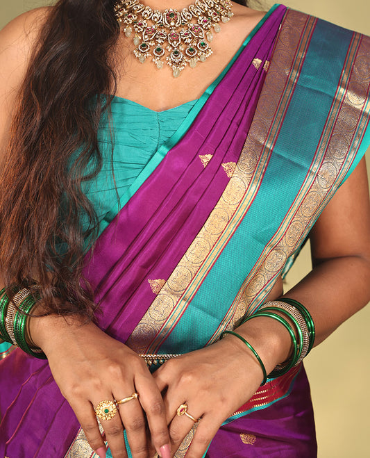 Purple Vasundhara Silk Saree, Beautifully Bedecked with Kamalam Buttas on Its Body, Complemented by a Captivating Contrast Border of Muthu, Chakram, and Mayil Kann Designs, Grand Jaal Pallu, and Paired with a Contrast Blouse