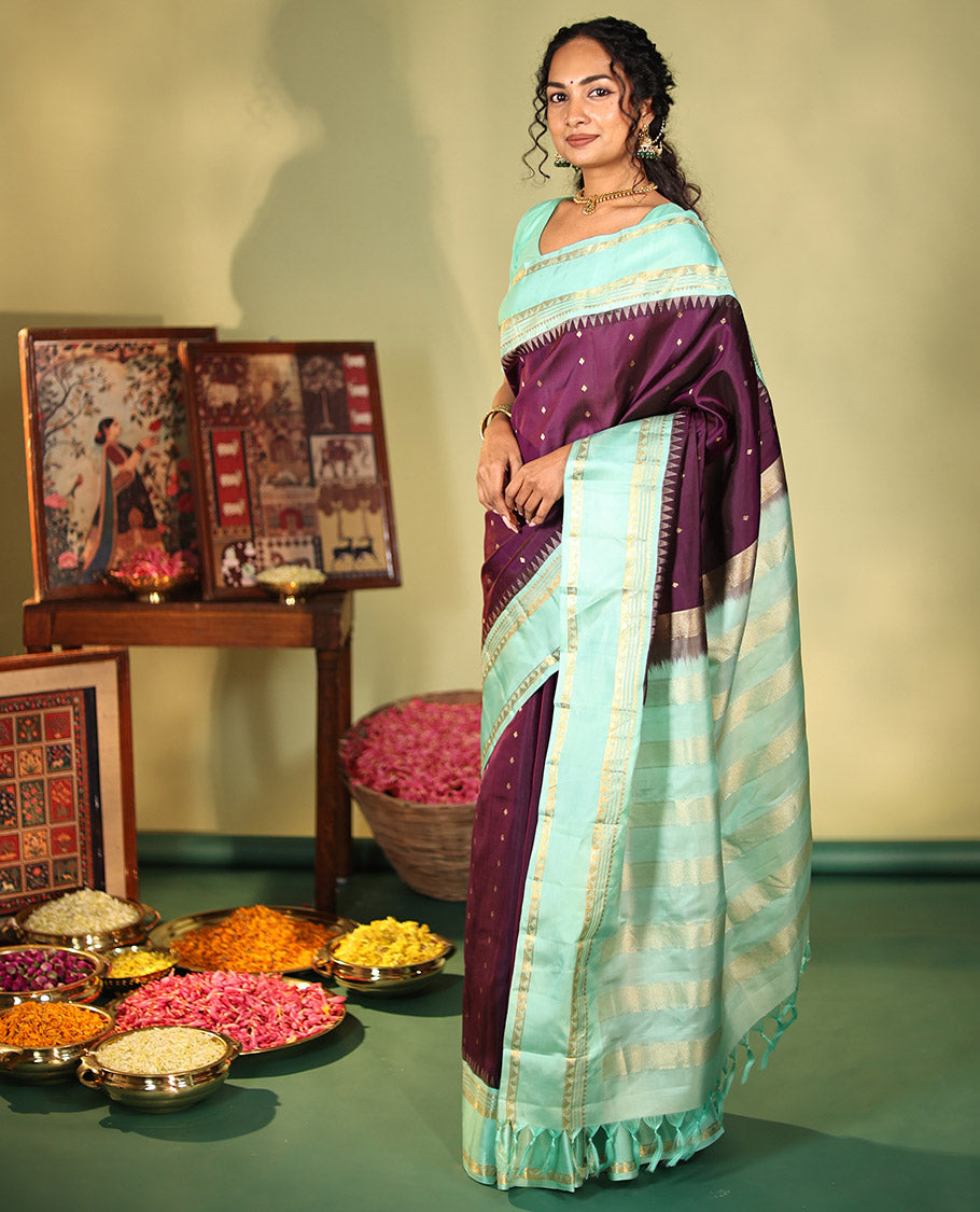 Purple Vasundhara Silk Saree, Spotlighted With Zari Buttas All Across Its Body, Complemented by Captivating Contrast Rettai Pettu Border of Thazampoo Rekku, Muthu, And Manga Designs, a Gleaming Zari Design Pallu, And Paired With a Contrast Blouse