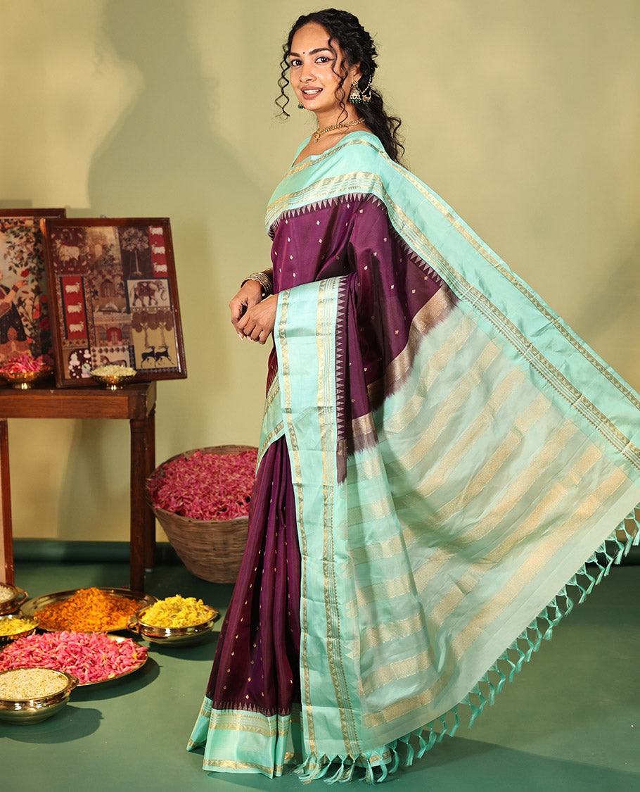 Purple Vasundhara Silk Saree, Spotlighted With Zari Buttas All Across Its Body, Complemented by Captivating Contrast Rettai Pettu Border of Thazampoo Rekku, Muthu, And Manga Designs, a Gleaming Zari Design Pallu, And Paired With a Contrast Blouse
