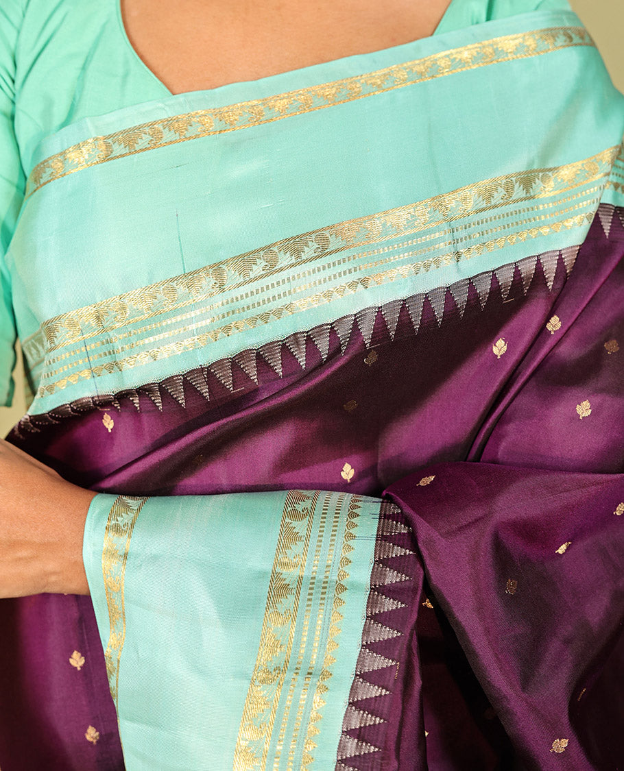 Purple Vasundhara Silk Saree, Spotlighted With Zari Buttas All Across Its Body, Complemented by Captivating Contrast Rettai Pettu Border of Thazampoo Rekku, Muthu, And Manga Designs, a Gleaming Zari Design Pallu, And Paired With a Contrast Blouse