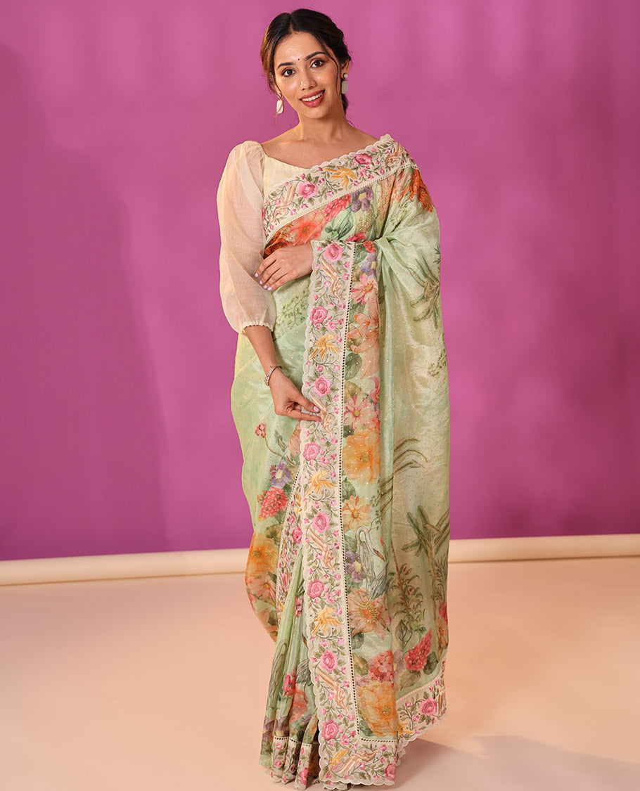 Green Dola Saree Gleamed Up with Gold Buttas and Colorful Tropical Floral Printed All Over Its Body, Complemented by a Contrast Scallop Floral Thread Embroidery Border, Pallu Depicts the Same Body Designs, and Paired with a Contrast Blouse