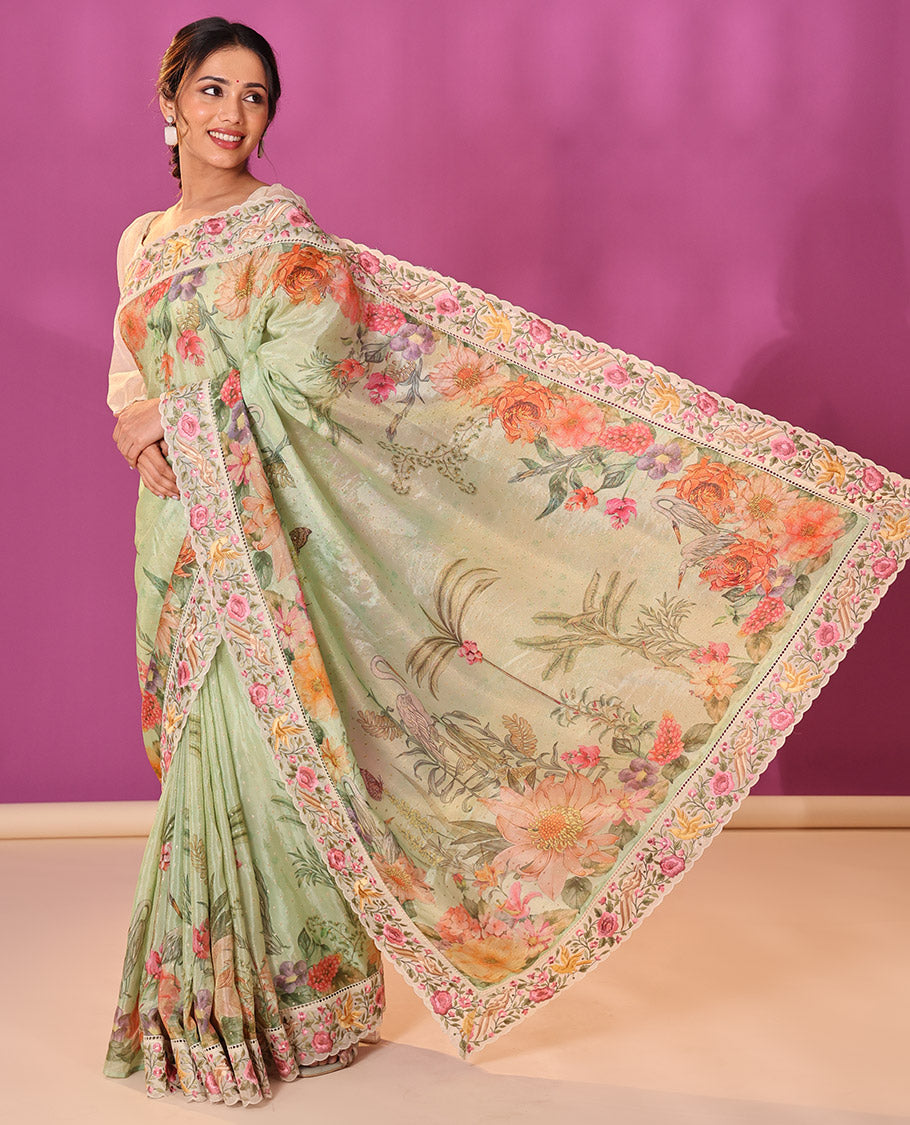 Green Dola Saree Gleamed Up with Gold Buttas and Colorful Tropical Floral Printed All Over Its Body, Complemented by a Contrast Scallop Floral Thread Embroidery Border, Pallu Depicts the Same Body Designs, and Paired with a Contrast Blouse