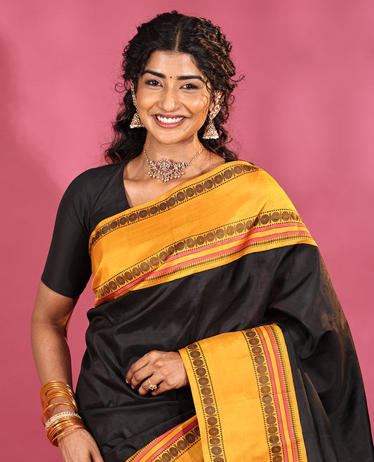 Black Plain Kanchipuram Silk Saree, Complemented by Captivating Contrast Rettai Pettu Border of Rekku, Muthu, and Rudraksham Designs, a Subtle Pallu of Thread Weave, and Paired with a Contrast Blouse