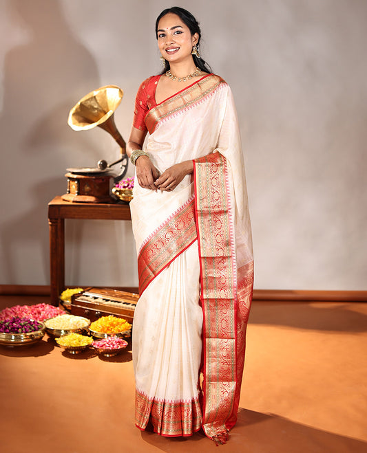Cream Vasundhara Silk Saree, Subtly Sparkled with Buttas And Checks On Its Body, Complemented by Captivating Contrast Border of Thazampoo Rekku, Muthu, Banaras, and Kodi Visiry Designs, Pallu Steeped with Manga Designs, And Paired with a Contrast Blouse