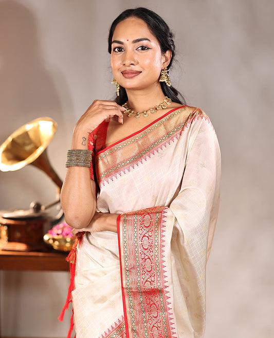 Cream Vasundhara Silk Saree, Subtly Sparkled with Buttas And Checks On Its Body, Complemented by Captivating Contrast Border of Thazampoo Rekku, Muthu, Banaras, and Kodi Visiry Designs, Pallu Steeped with Manga Designs, And Paired with a Contrast Blouse
