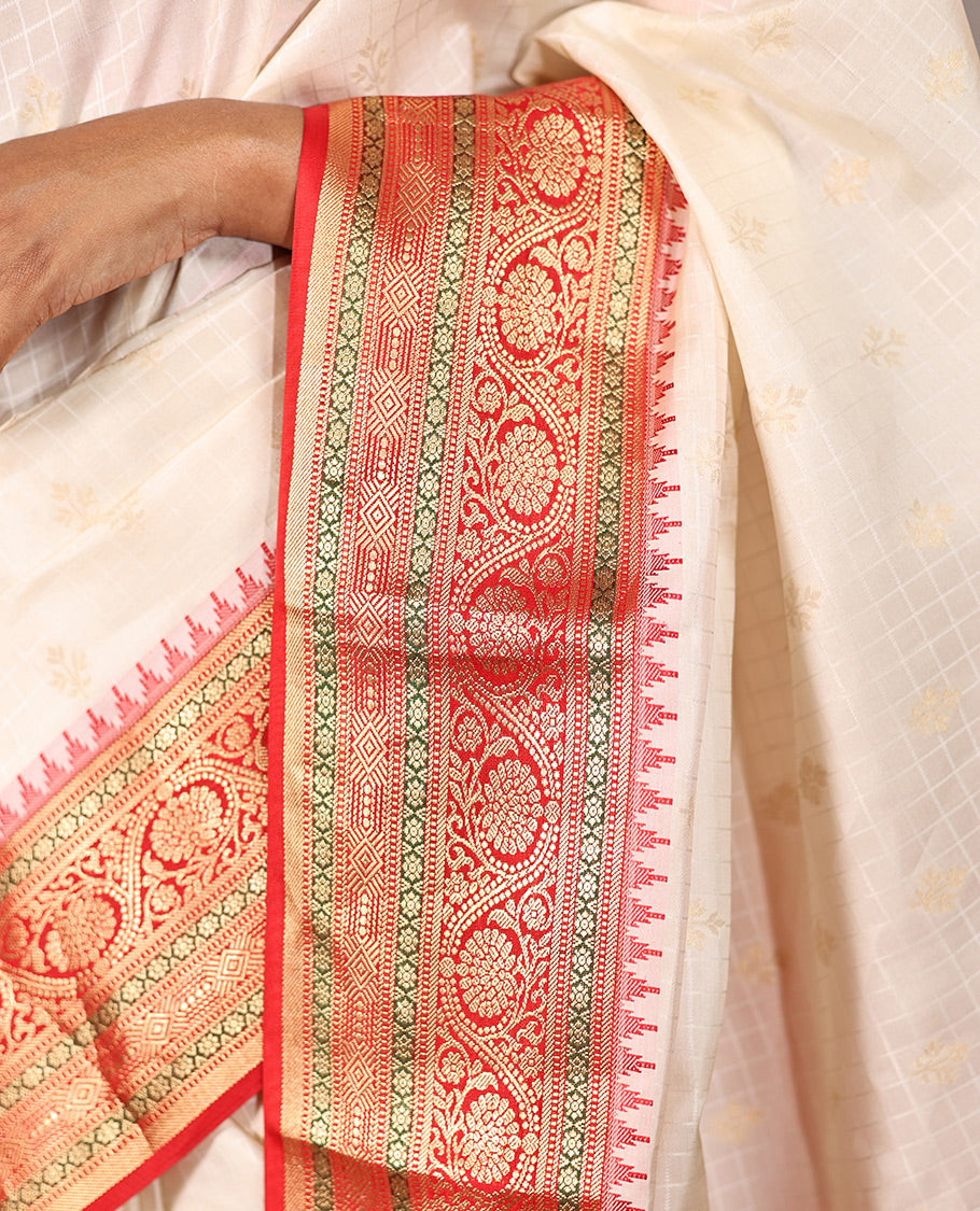 Cream Vasundhara Silk Saree, Subtly Sparkled with Buttas And Checks On Its Body, Complemented by Captivating Contrast Border of Thazampoo Rekku, Muthu, Banaras, and Kodi Visiry Designs, Pallu Steeped with Manga Designs, And Paired with a Contrast Blouse