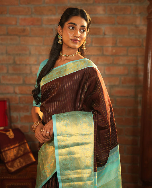 Brown Vasundhara Silk Saree Delicately Woven with Zari Buttas, Highlighted with a Contrast Border of Cross Kamalam, Mayil, Banaras, Yaanai, and Mayil Kann Designs, Pallu Grandly Woven with Jaal Designs, and Paired with a Contrast Blouse