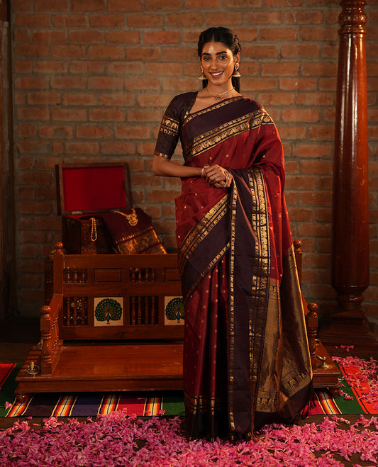 Maroon Vasundhara Silk Saree Decorated with Zari Buttas All Over Its Body, Complemented by a Contrast Rettai Pettu Border Steeped with Yaanai Motifs, Richly Detailed Pallu of Jaal Designs, and Paired with a Contrast Zari Bordered Blouse