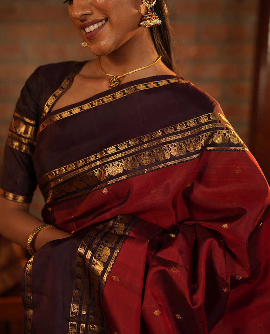Maroon Vasundhara Silk Saree Decorated with Zari Buttas All Over Its Body, Complemented by a Contrast Rettai Pettu Border Steeped with Yaanai Motifs, Richly Detailed Pallu of Jaal Designs, and Paired with a Contrast Zari Bordered Blouse
