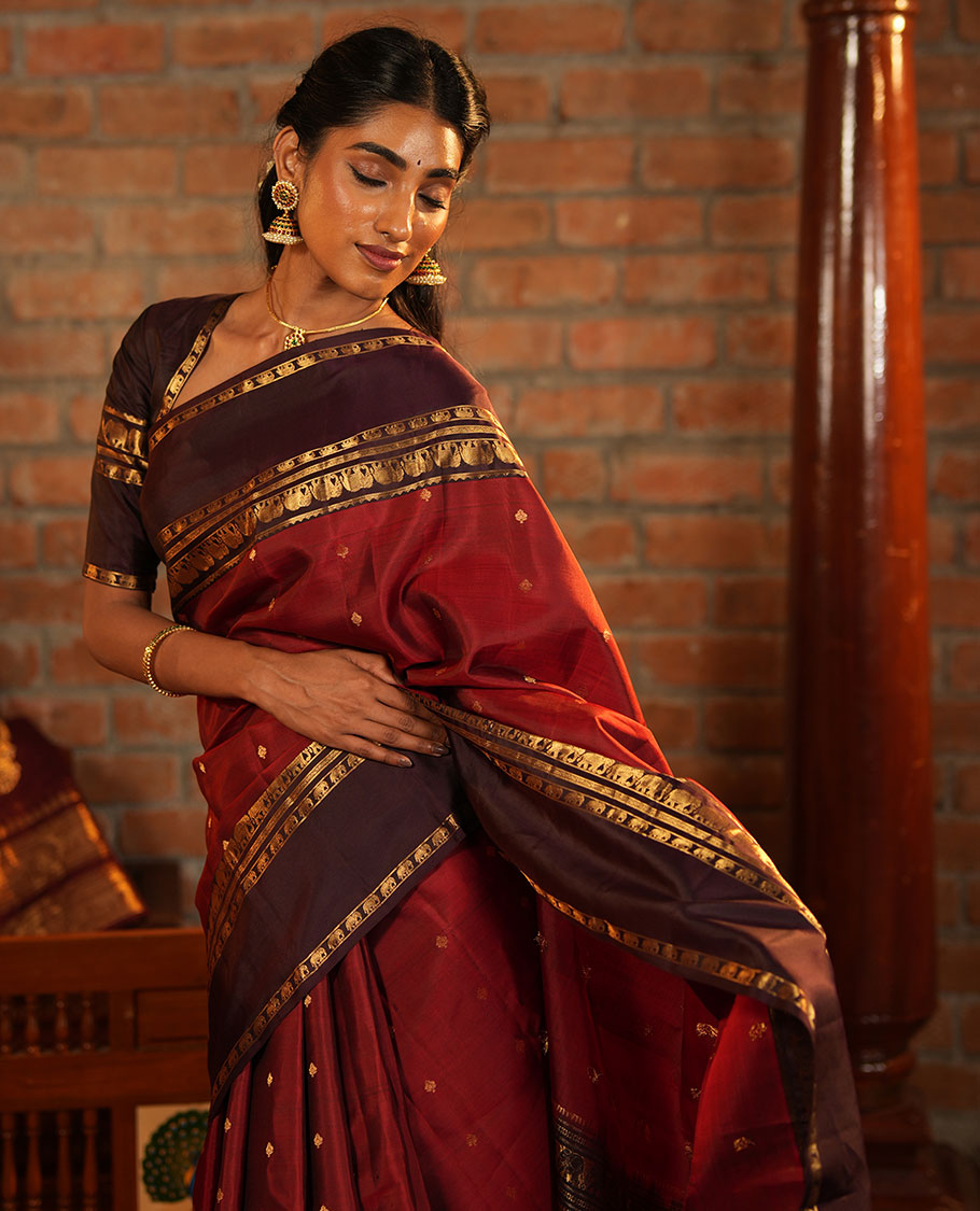 Maroon Vasundhara Silk Saree Decorated with Zari Buttas All Over Its Body, Complemented by a Contrast Rettai Pettu Border Steeped with Yaanai Motifs, Richly Detailed Pallu of Jaal Designs, and Paired with a Contrast Zari Bordered Blouse