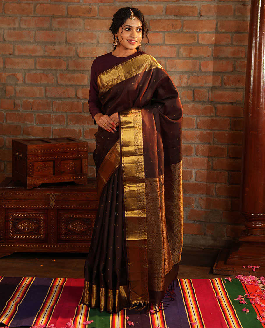 Brown Vasundhara Silk Saree Beautified with Zari Buttas All Over Its Body, Gleamed Up with a Zari Border of Thilakam Mokku, Kathir, Rudraksham, and Arumbu Manga Designs, Majestically Detailed Pallu of Jaal Designs, and Comes with a Matching Blouse