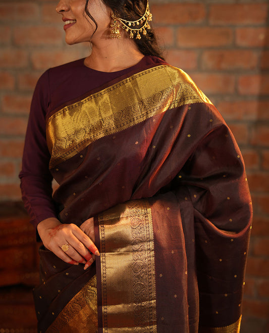 Brown Vasundhara Silk Saree Beautified with Zari Buttas All Over Its Body, Gleamed Up with a Zari Border of Thilakam Mokku, Kathir, Rudraksham, and Arumbu Manga Designs, Majestically Detailed Pallu of Jaal Designs, and Comes with a Matching Blouse